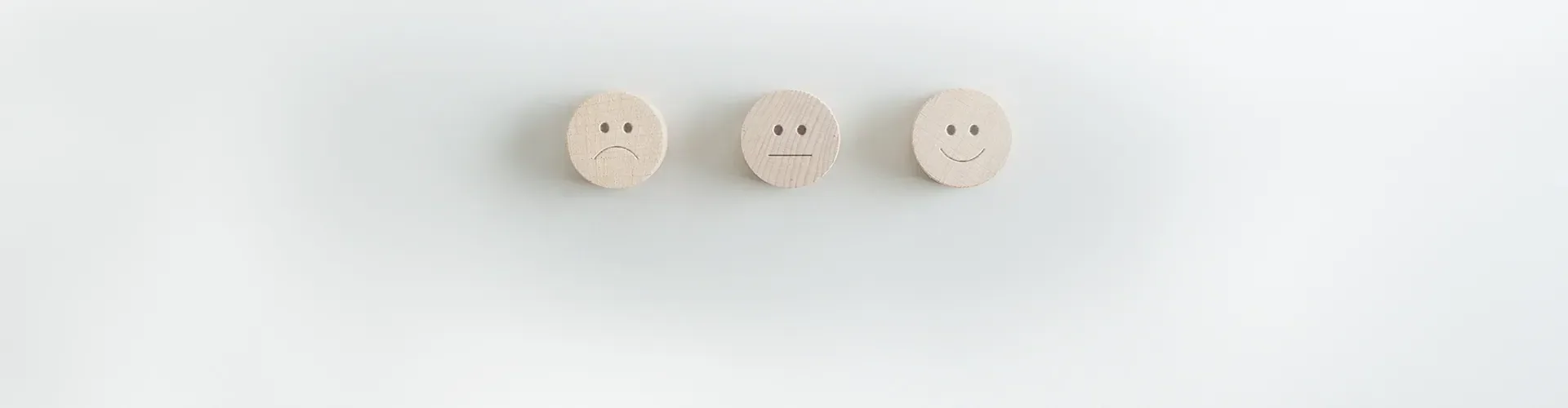 Drei Bewertungs-Smileys aus Holz – Feedback zur Pflege von PRICA