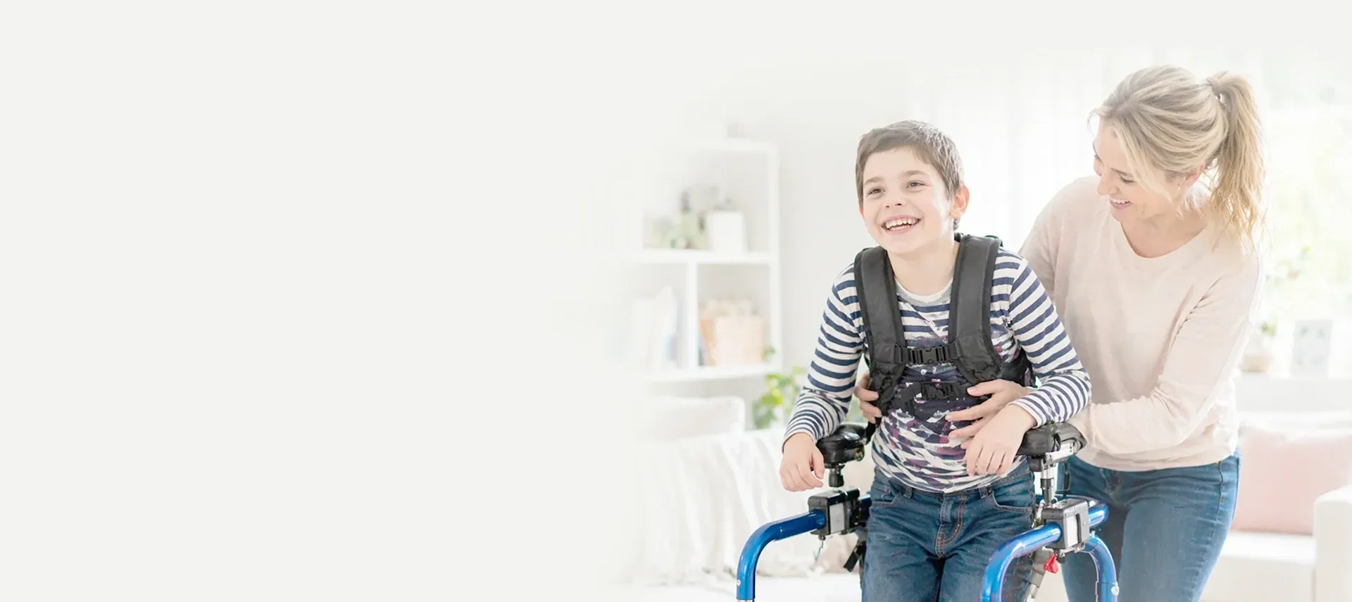 Junge mit Gehhilfe lacht gemeinsam mit seiner Mutter
